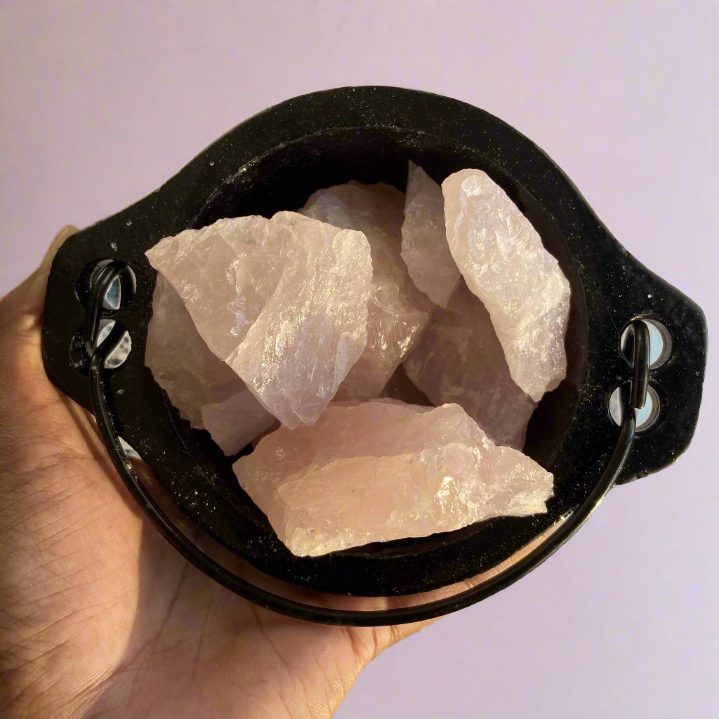 Raw fish pieces in a black pot held by a hand on a light background